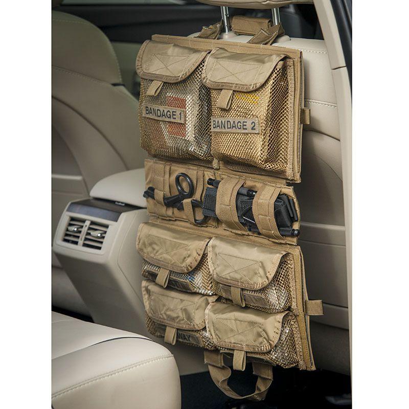 Ein Chinook Medical Panel aus beige-farbenem Mesh hängt an einer Autositzelehne, gefüllt mit beschrifteten Fächern für Verbände und medizinische Ausrüstung.