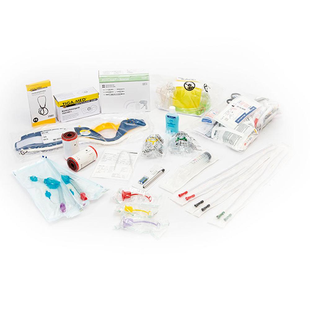 Verschiedene medizinische Komponenten wie Röhrchen, Verbandsmaterial und Instrumente aus dem Basis Füllung DIN 13155 Set liegen lose verteilt nebeneinander.