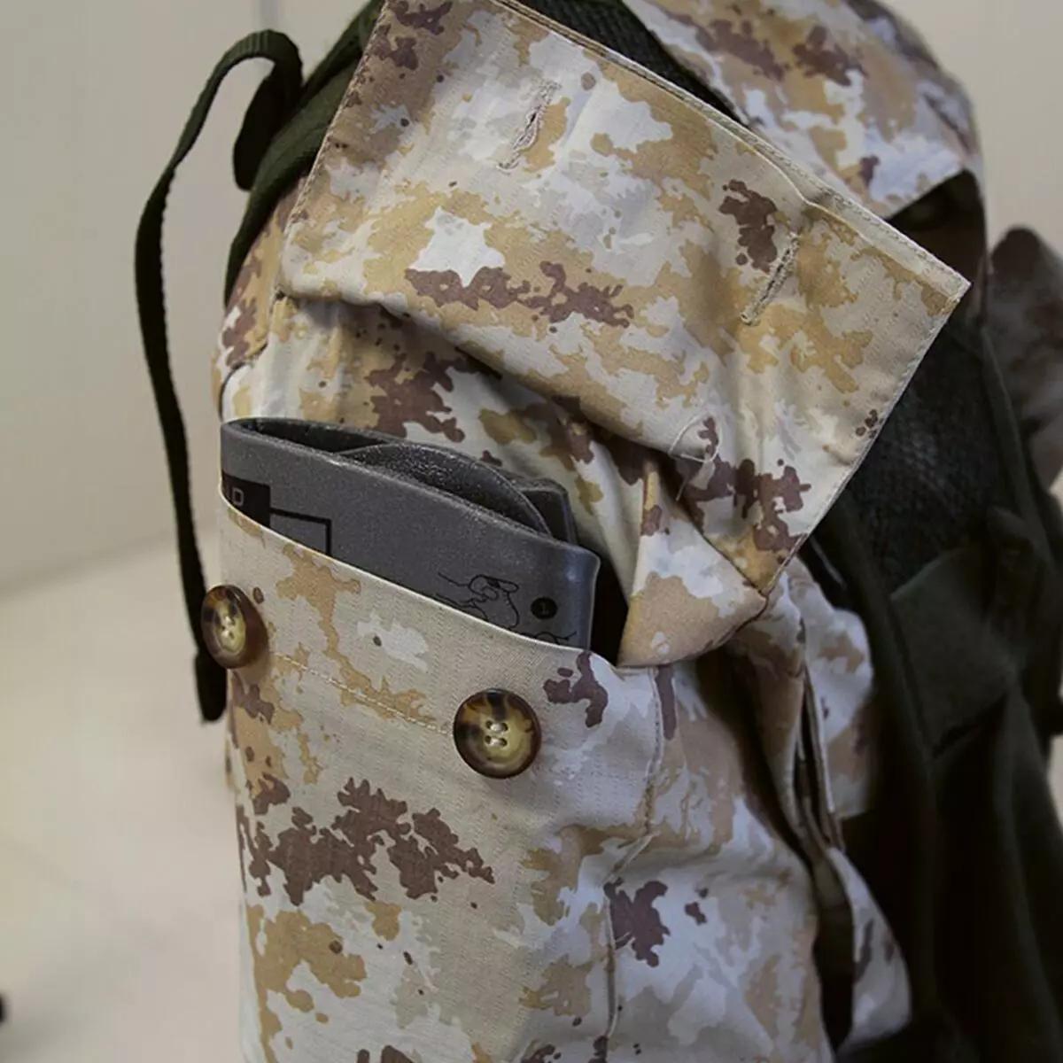 Eine Person trägt den Immobilisationskragen Necklite™ - Grau, der mit Klettverschluss und beweglicher Kinnauflage unter einer tarnfarbenen Jacke angelegt ist.