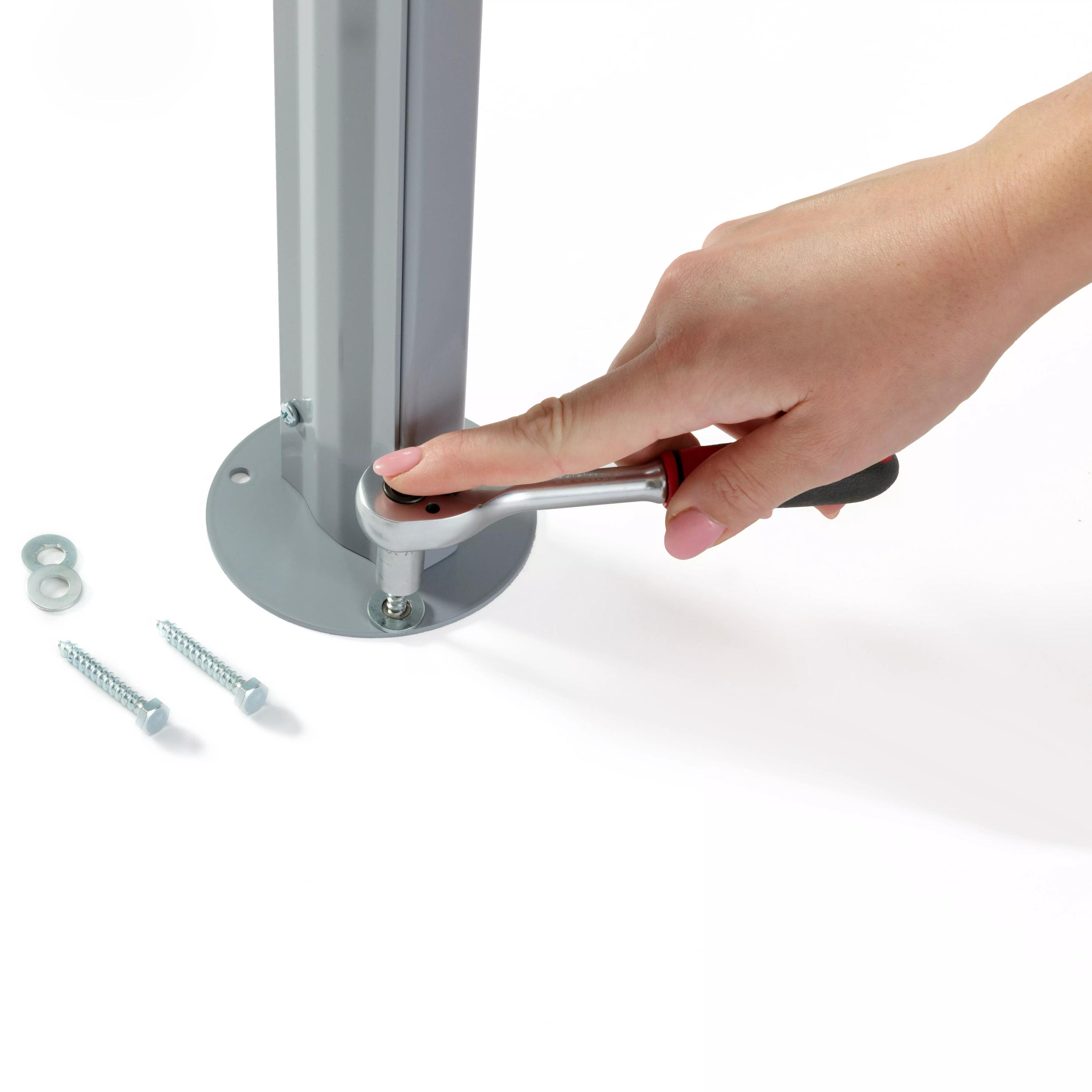 Eine Hand mit pinkem Nagellack zieht eine Schraube an einem grauen Metallpfosten des Weroflex® Station - 3-Seiten Komplett-Set mit einem silbernen, roten Schraubenschlüssel fest.