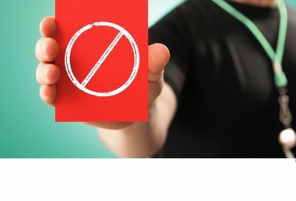 Die Hand einer Person hält eine rote Karte mit weißem Verbotssymbol.