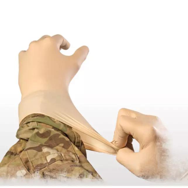 Zwei Hände in Tarnkleidung ziehen einen NAR Bear Claw™ Nitril Einmalhandschuh an, dessen Fingerspitzen texturiert und das Material hochelastisch ist.