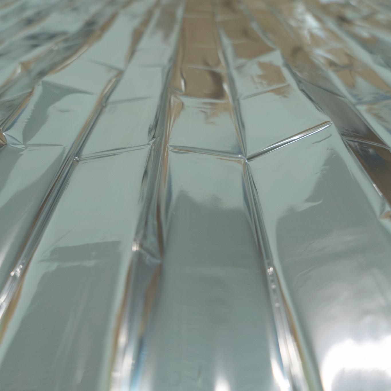 Nahaufnahme einer silbern glänzenden, gerippten WERO MED-X® Rettungsdecke mit gefalteter, geknitterter und glatter Oberfläche.