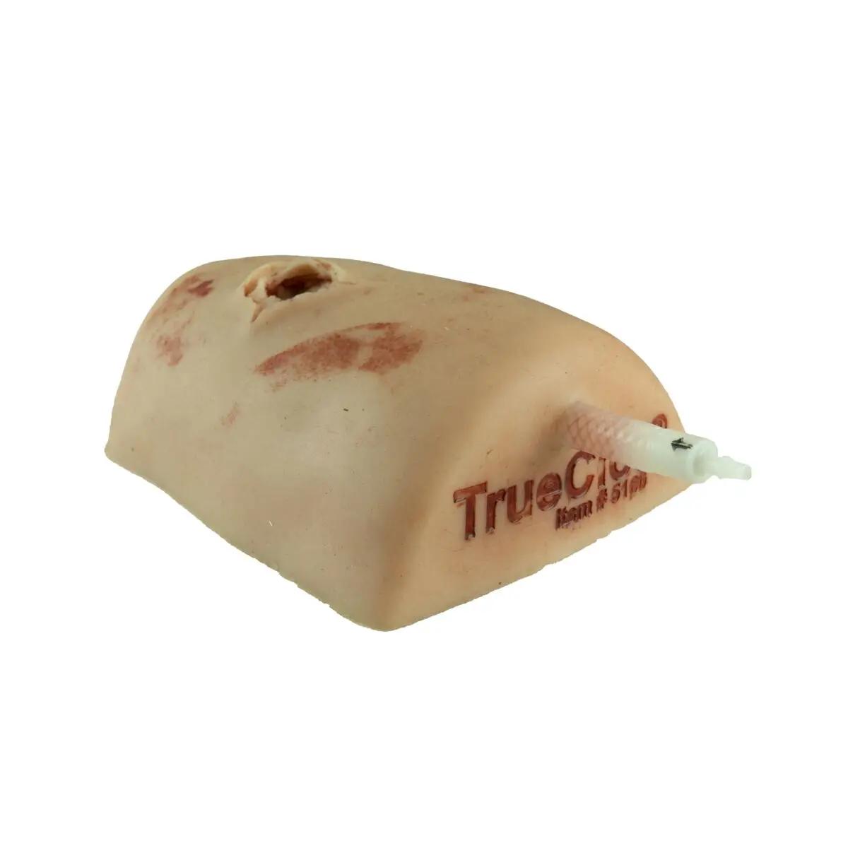 TrueClot® Wound Packing Task Trainer Schusswunden zeigt einen beigen Medizin-Dummy mit simulierter Schusswunde und angebrachtem weißen Schlauch.