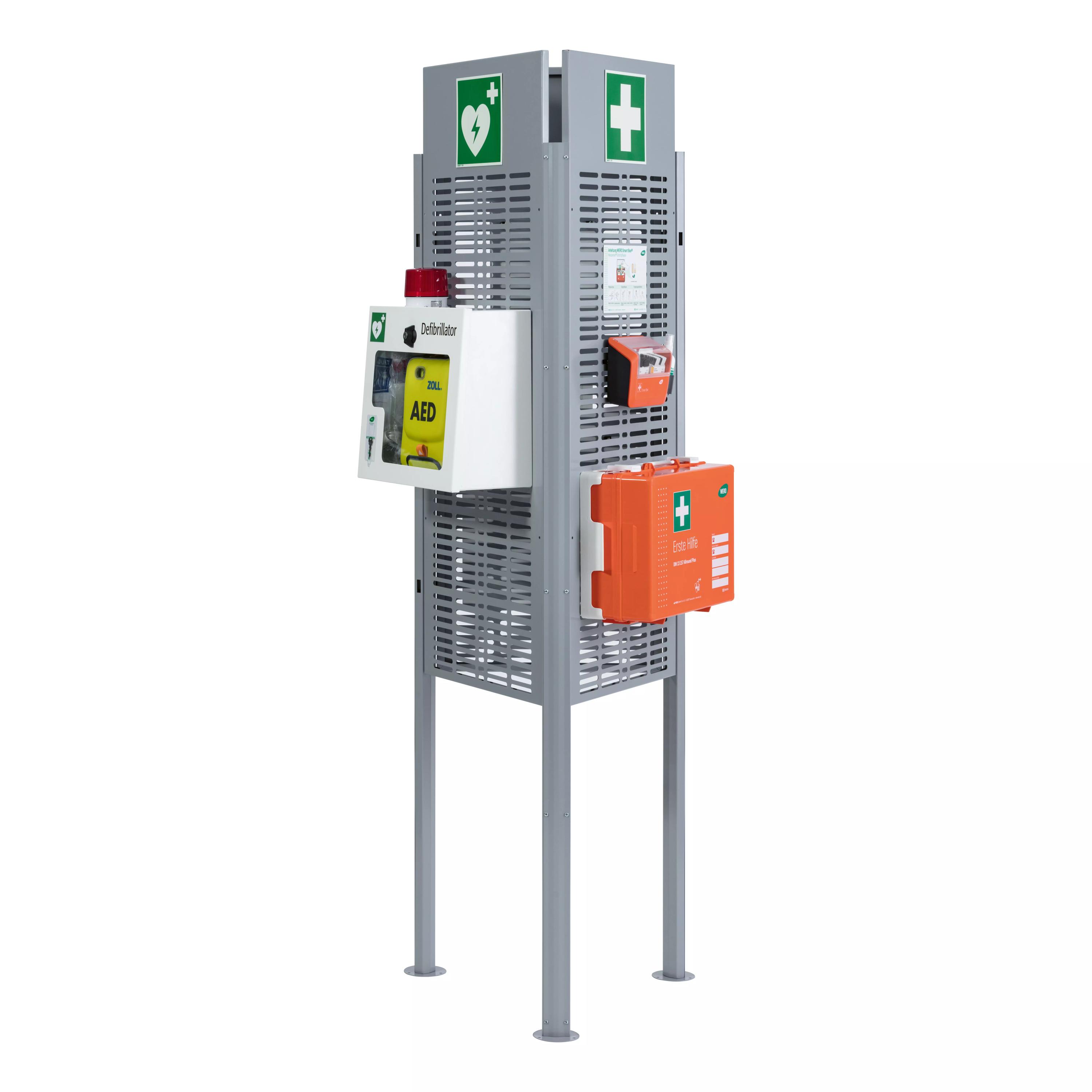 Ein aufrechter Weroflex® Station - 3-Seiten Komplett-Set Stand mit AED-Fach, orangefarbener Erste-Hilfe-Box und erweiterbaren Notfallfächern.