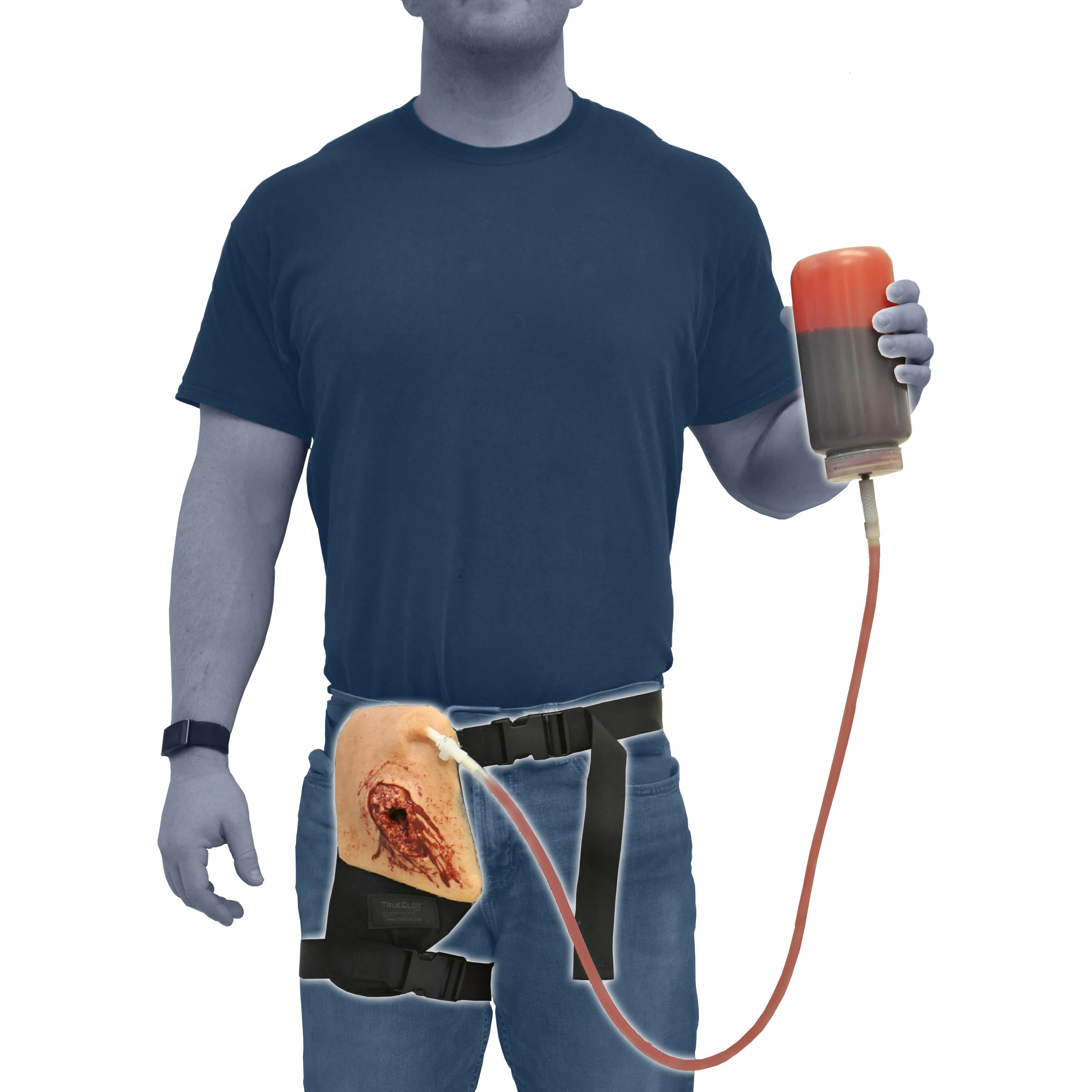 Eine Person trägt den TrueClot® Leisten Wound Packing Trainer als schwarze Gürteltasche mit blutender Beinsimulation und hält eine Flasche Kunstblut in der Hand.