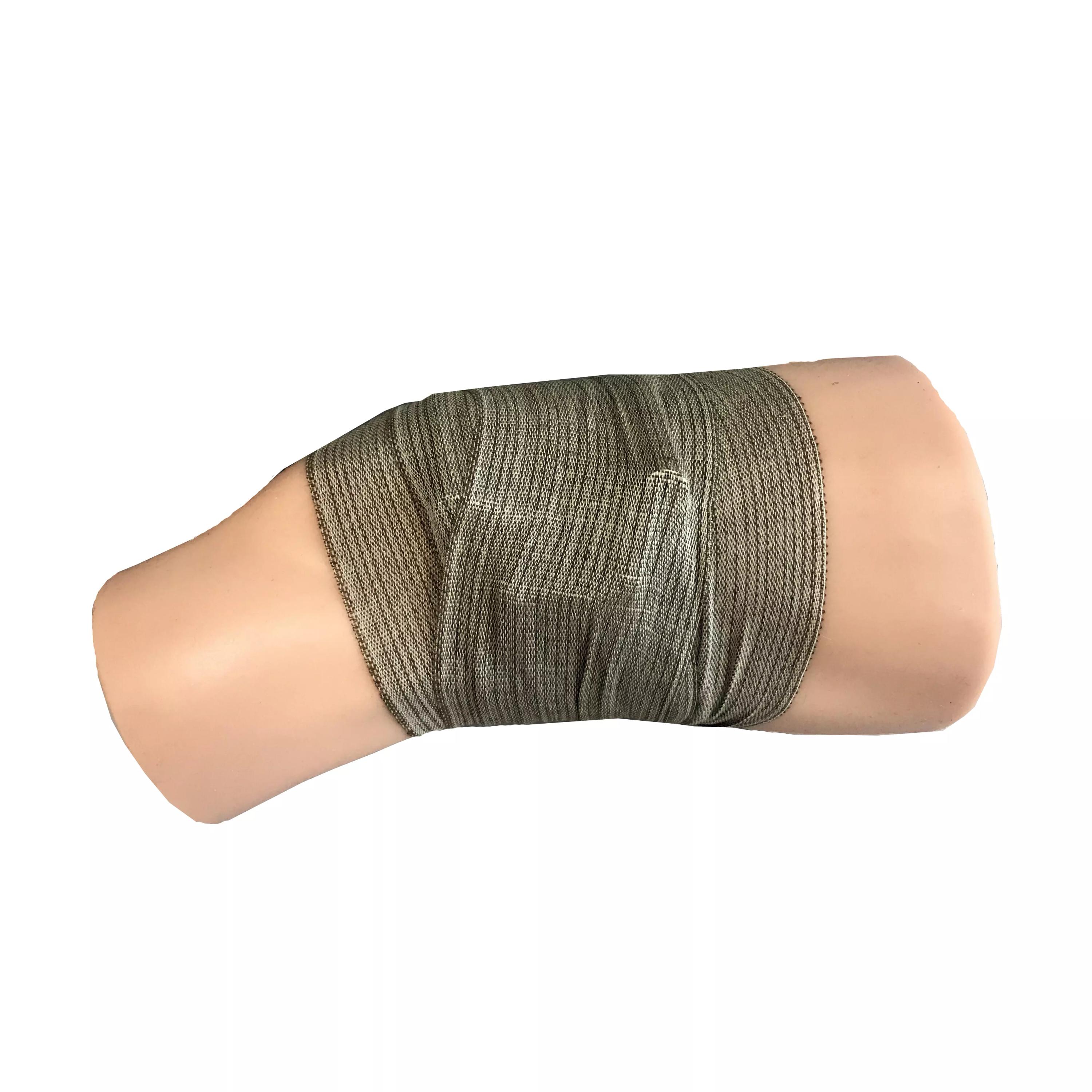 Ein TrueClot® PCT3 Trainer Modell zeigt ein hellbraunes Bein, das von einer dunkelgrünen Bandage mit Befestigungen vollständig umwickelt ist.