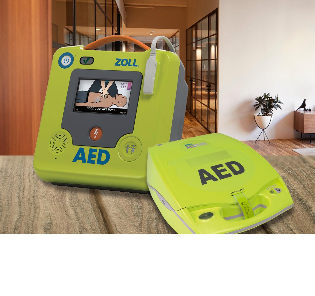 Zwei grüne ZOLL AED-Defibrillatoren in Nahaufnahme. Im Hintergrund ein Büro.