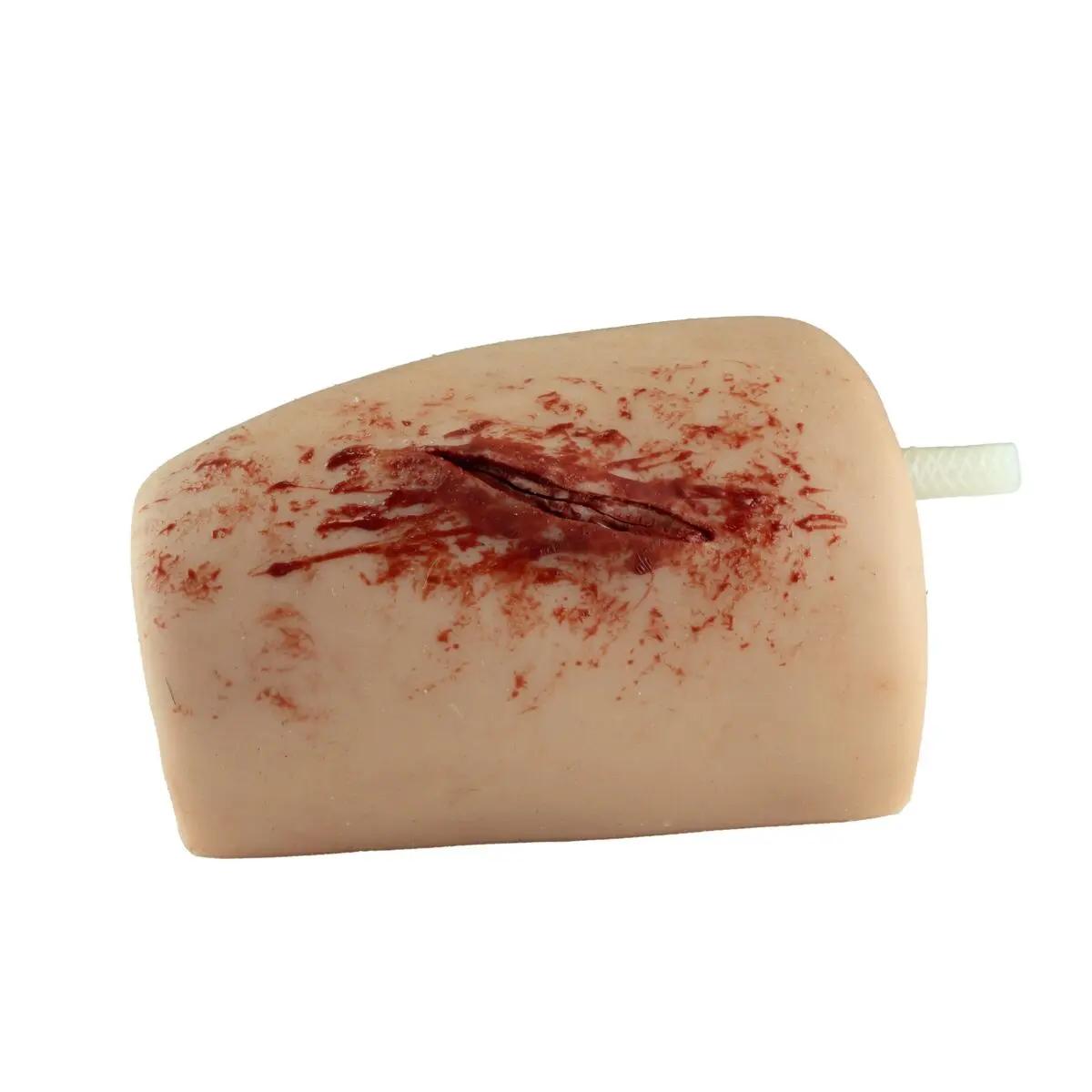 Ein TrueClot® Wound Packing Trainingssystem Schnittwunde zeigt eine realistische, längliche Schnittwunden-Attrappe mit simulierten Blutspuren und weißem Verbindungsstab.
