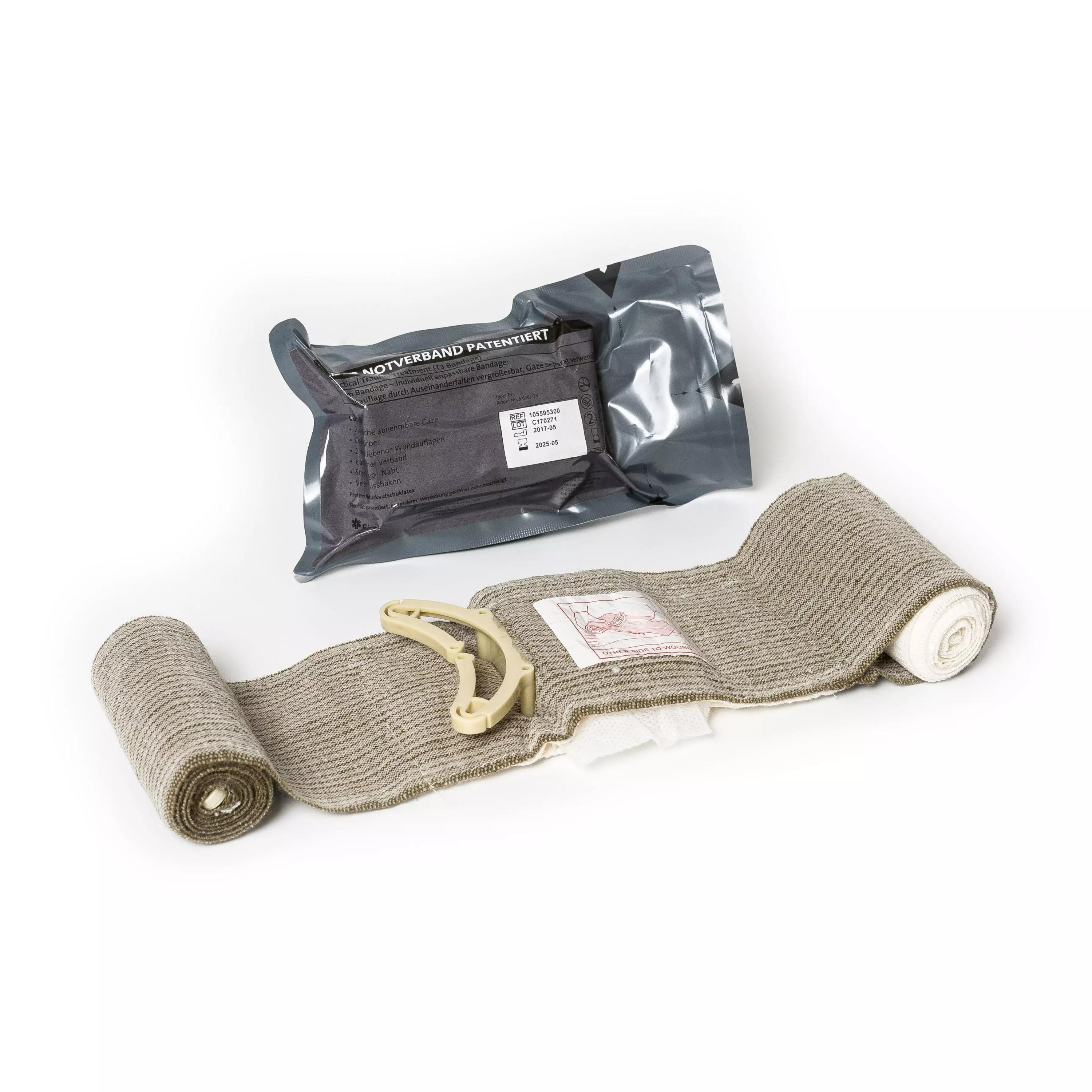 Die T3 Bandage™ liegt ausgerollt neben beige-farbener Mullbinde und einem kleinen Klammerclip, darüber ein geöffnetes schwarzes Etui.
