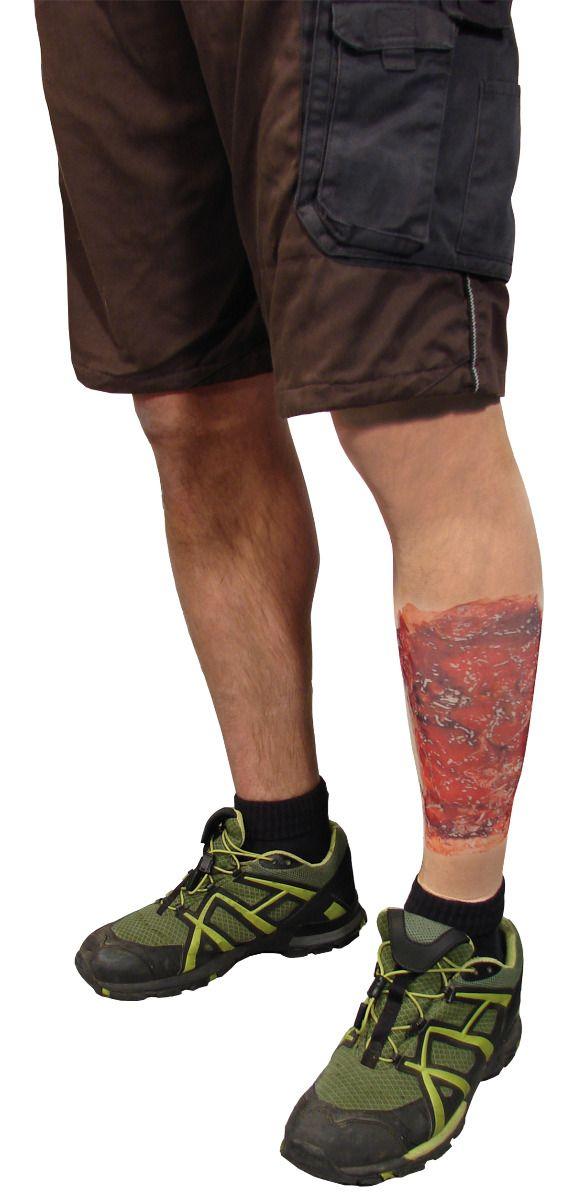 Eine Person trägt RAPID Trauma-Simulation am linken Unterschenkel; das elastische Tattoo zeigt eine realistisch wirkende, blutige Verletzung.