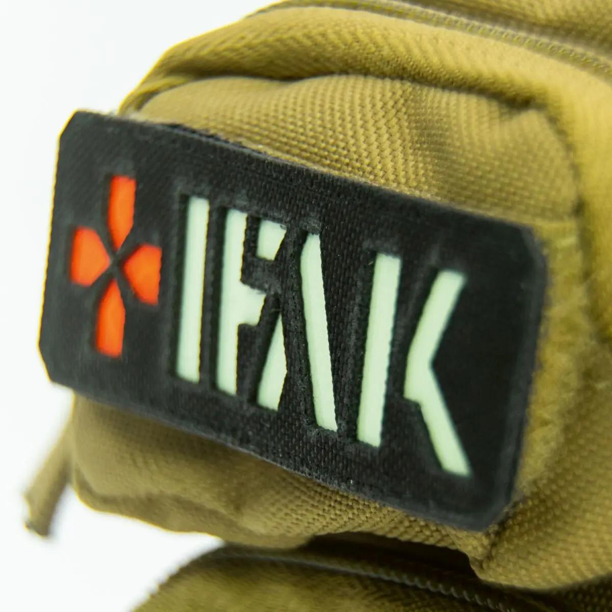 Ein schwarzer IFAK-Aufnäher mit rotem Kreuz ist auf dem beigen WERO MED-X® Mini Notfallrucksack angebracht, der ultra-kompakt gestaltet ist.