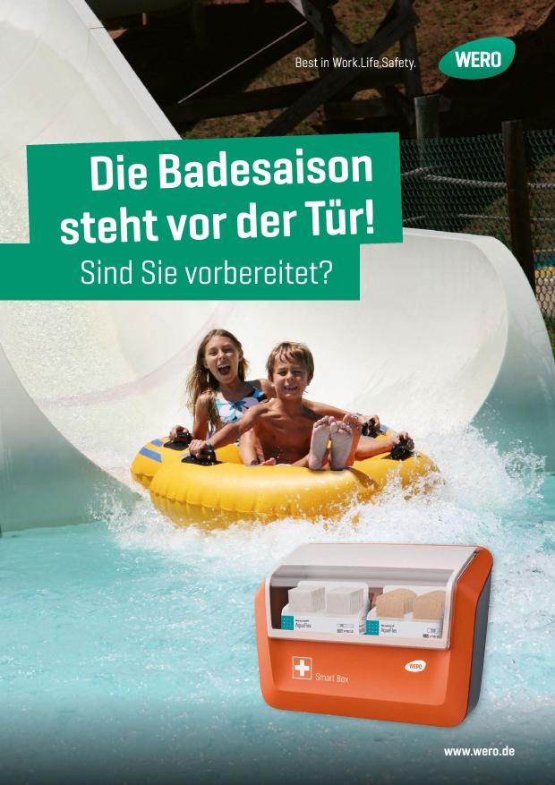 Zwei Kinder rutschen auf einem gelben Schwimmreifen eine Wasserrutsche hinab, im Vordergrund steht eine rote Smart Box mit Erste-Hilfe-Symbolen.