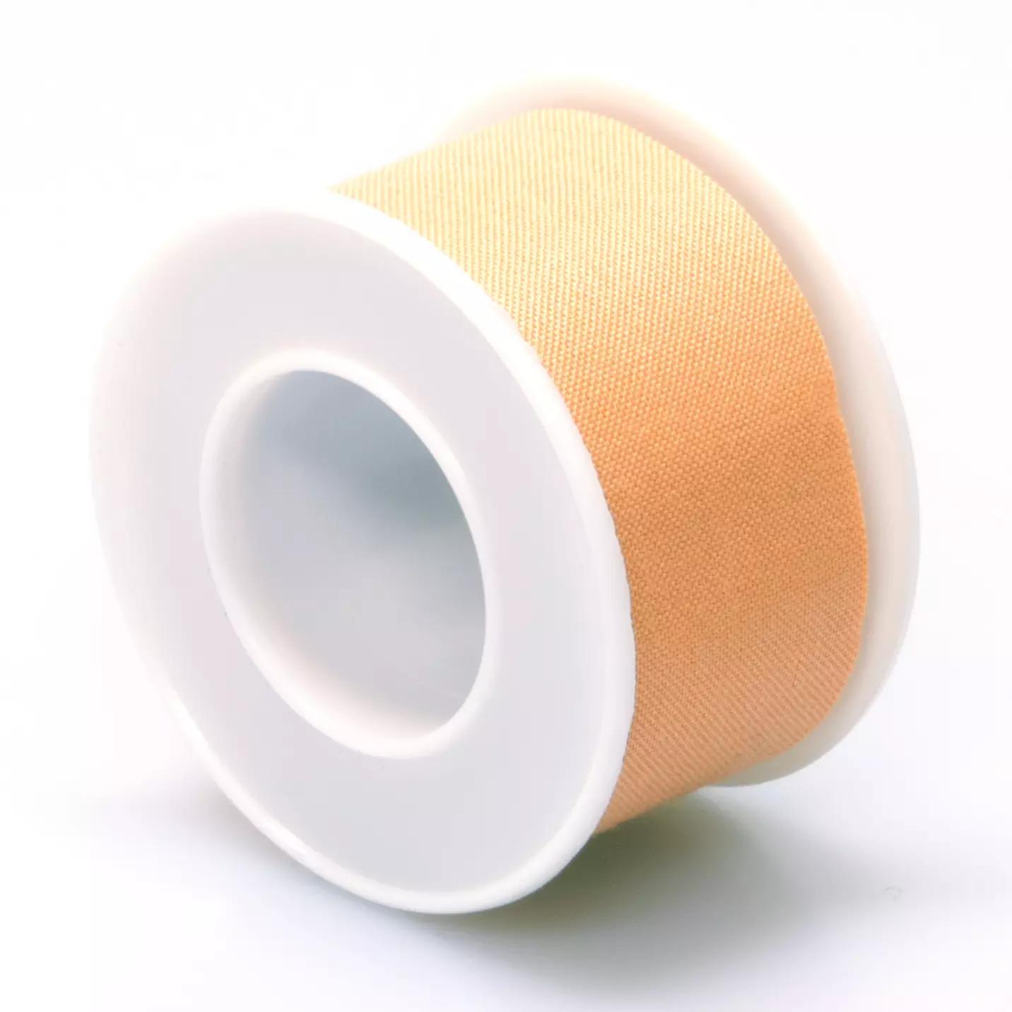 Eine neue, unbenutzte Rolle Micaplast-Spulenpflaster, starr, 5 m x 2,5 cm, liegt auf einem weißen Kunststoffspulenkern.