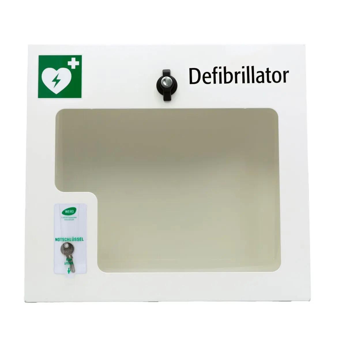 Weißer AED-Wandschrank (gebraucht) mit Alarmfunktion, schwarzem Griff, Sichtfenster, grünem Herzsymbol, Kreuz und abschließbarem Verschluss.