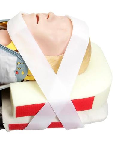 Eine CM T-Fix™ Kopffixierung sichert den Kopf einer Trainingspuppe mit weißem Band sanft auf zwei Schaumstoffpolstern.