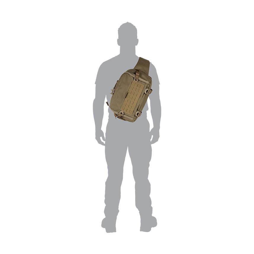 Eine Person trägt eine 5.11 UCR SLINGPACK Notfalltasche mit quer laufendem Gurt, mehreren Innenfächern und Kompressionsriemen über der Schulter.