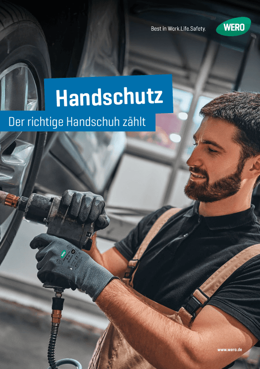 Ein Mann in brauner Latzhose montiert ein Autoreifen mit einem pneumatischen Schlagschrauber.