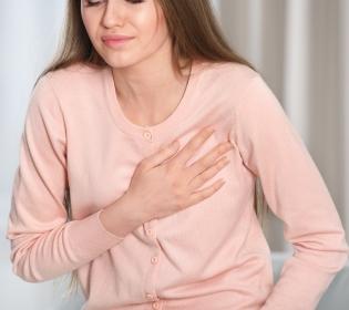 Frau mit langen, hellbraunen Haaren trägt ein rosafarbenes, langärmliges Hemd und blickt nach unten zur Seite.
