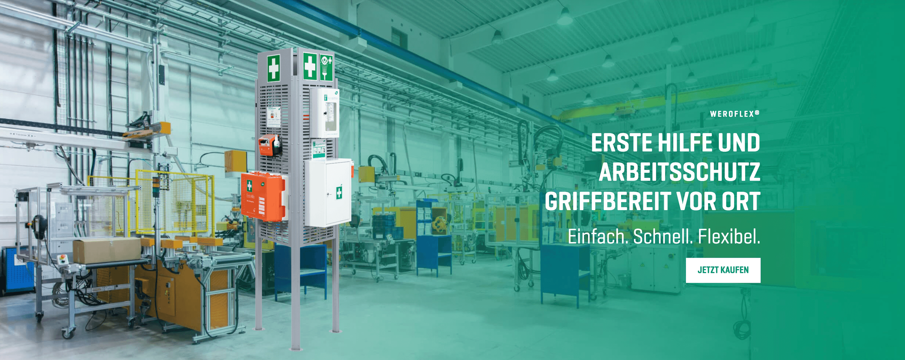 Zentrale Erste-Hilfe-Station mit grünem Kreuz und Alarm im Industrie-Lager, umgeben von Förderband, Metallboxen und Werkbänken.