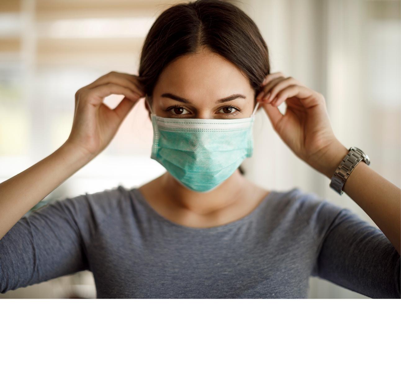 Eine Frau zieht einen grünen, 3-lagigen Mundschutz an