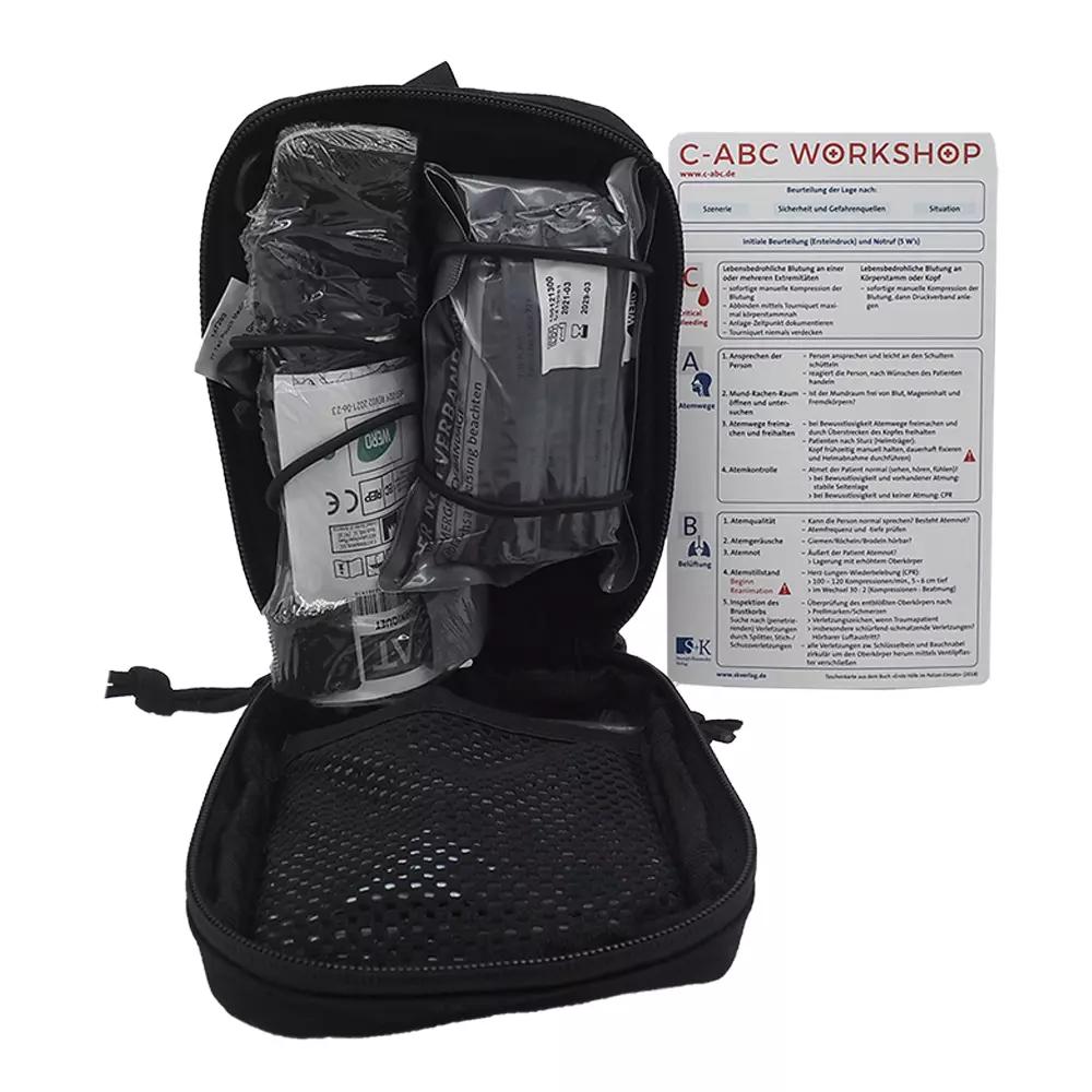 Das C-ABC Adventure First Aid Pack ist geöffnet und zeigt Multi-Tool, bandagierte Verbände, antiseptische Tücher und eine kleine Desinfektionsflasche.