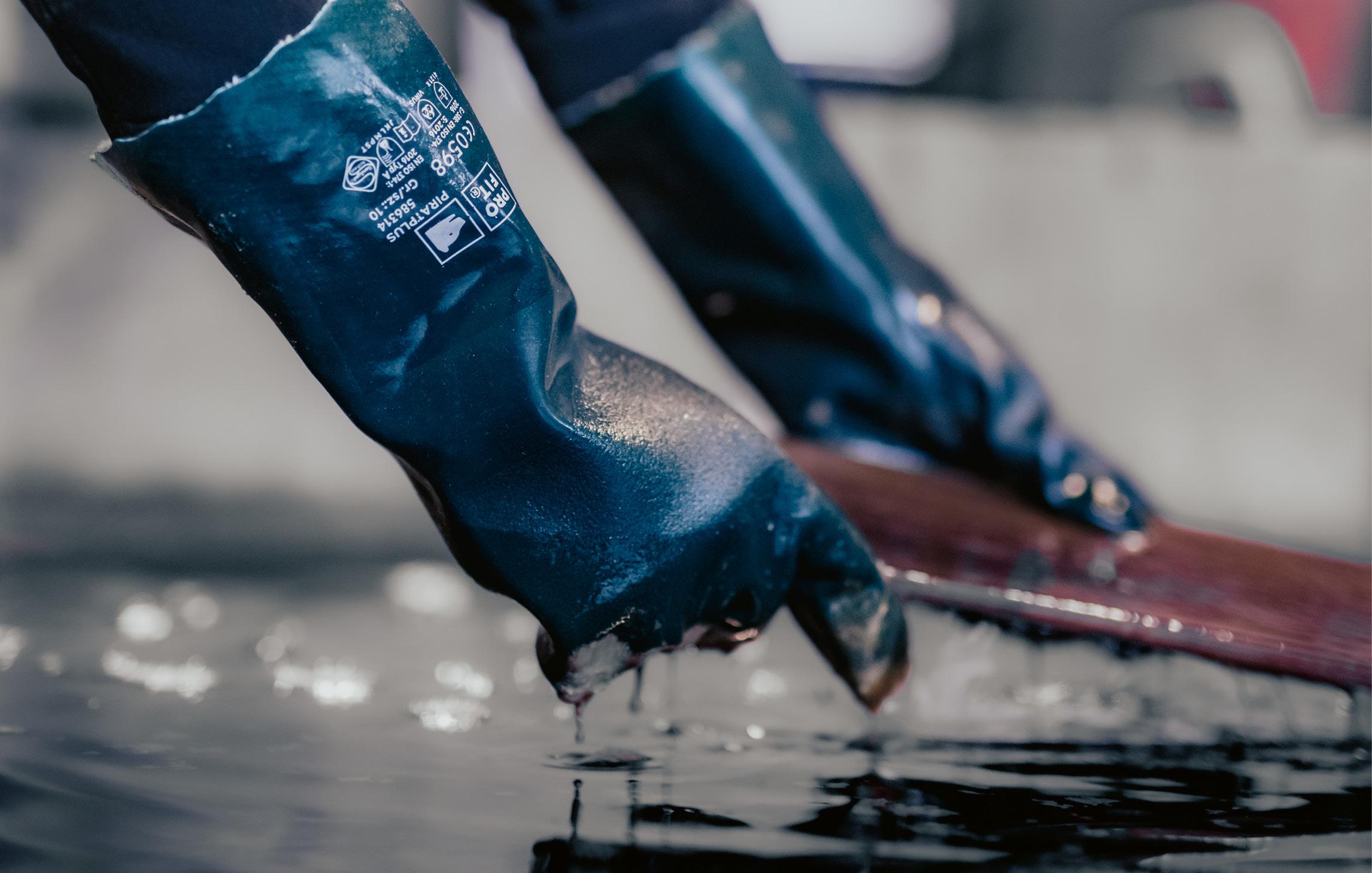 Chemiehandschuhe heben eine Platte aus einer Flüssigkeit