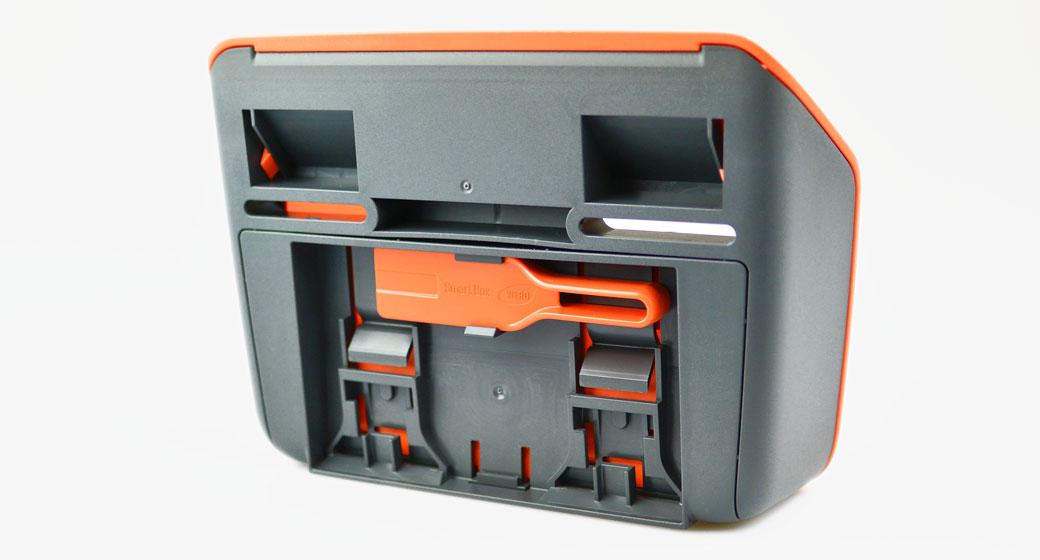 SmartTrack Gerät mit orangefarbenem Kopf, grauem Gehäuse, rotem Griff und mehreren funktionalen Aussparungen