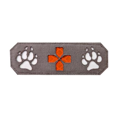Rechteckiger Patch Lasercut K9 + rotes Kreuz - K9 aus grauem Stoff, mittig rotes Kreuz mit strukturierter Oberfläche und orangefarbene Pfotenabdrücke.