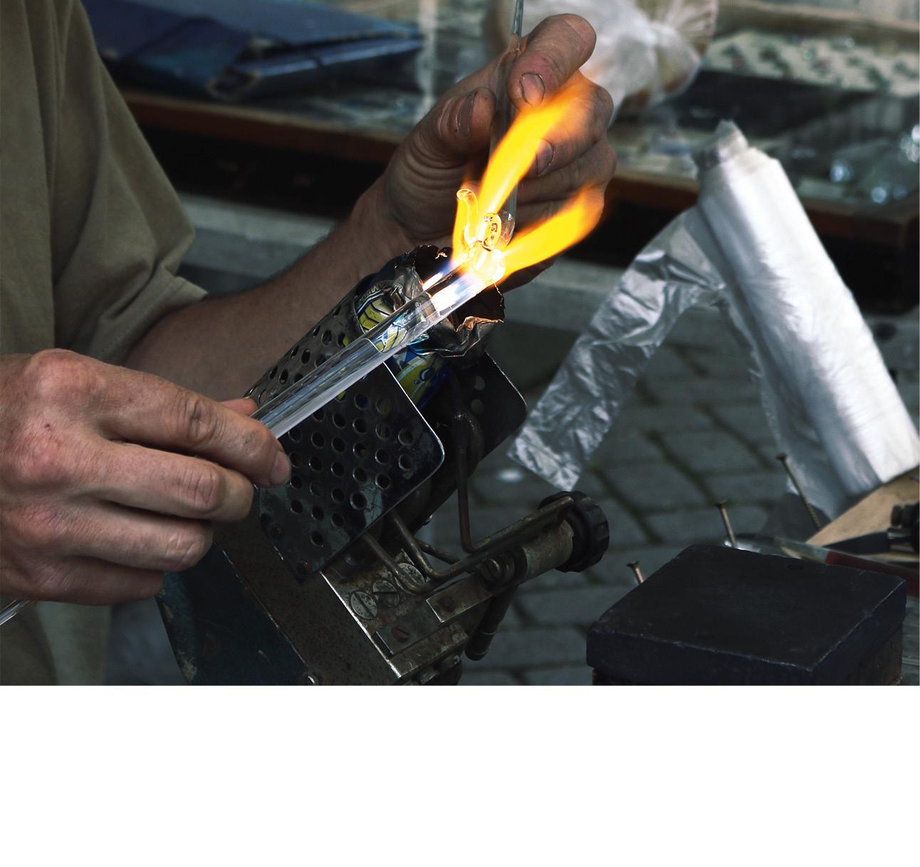 Eine Person bearbeitet Glas an einer heißen offenen Flamme.