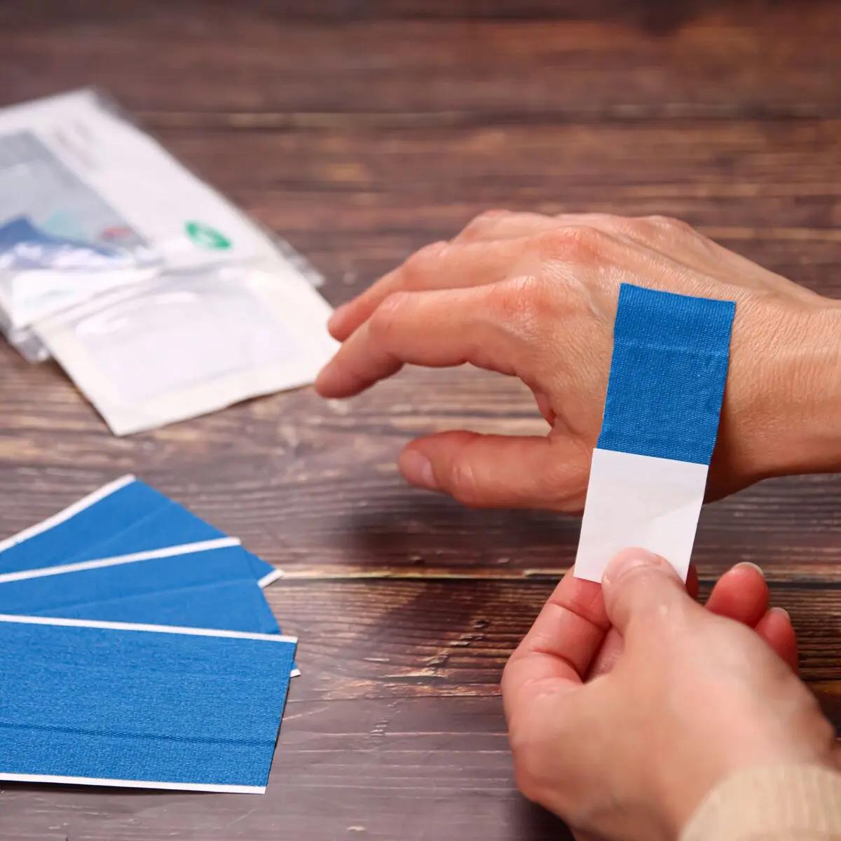 Zwei Hände hantieren mit einem blauen Wundschnellverband Weroplast® PowerDetect, detektierbar dank Aluminiumstreifen und längs- sowie querelastisch.