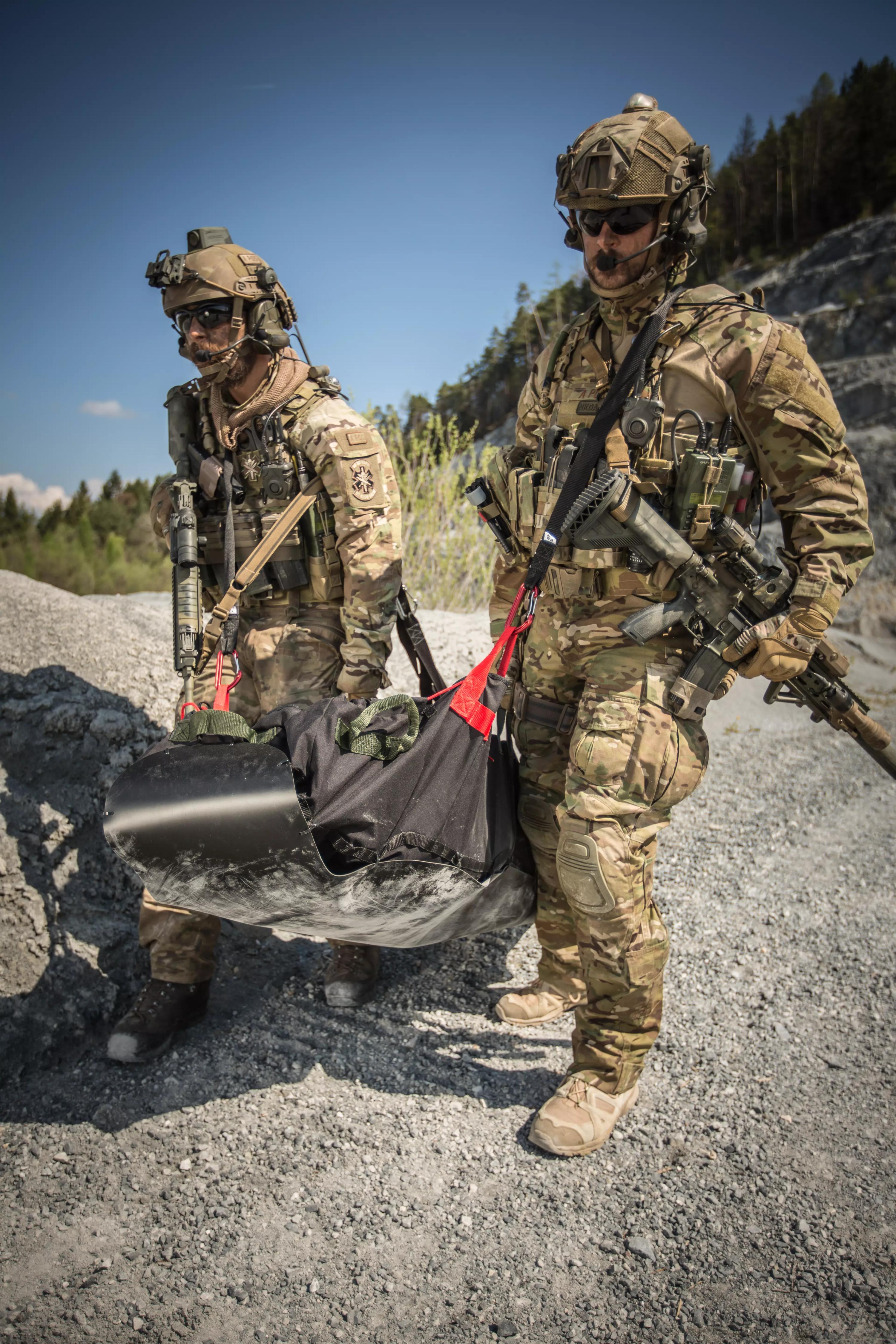 Zwei Soldaten im Manöver tragen das Xtract™ SR Module Rettungsset in taktischer Ausrüstung auf felsigem Waldboden.