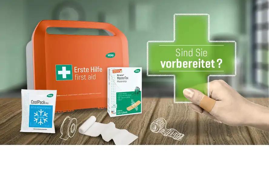 Ein orangefarbener Erste-Hilfe-Kasten steht neben einem CoolPack Mini, einer MasterTex Pflasterbox und einer Hand mit Pflaster.