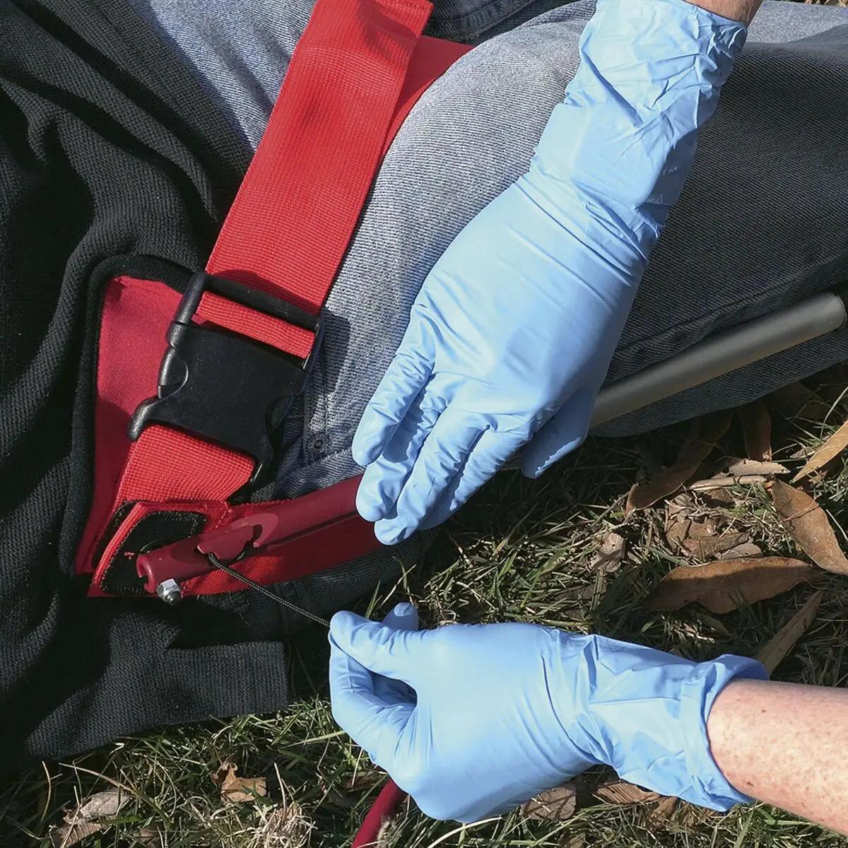 Eine Person legt mit blauen Handschuhen die Slishman Traction Splint (STS) GEN. 2 am Bein an, zeichnet sich durch vielseitigen Einsatz und schnelles Anlegen aus.