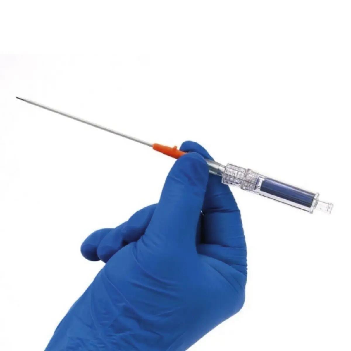 Eine Hand in blauer Schutzhandschuh hält einen Capnospot® Pneumothorax Dekompressionsindikator mit orangefarbener Nadel und transparenter Kammer.