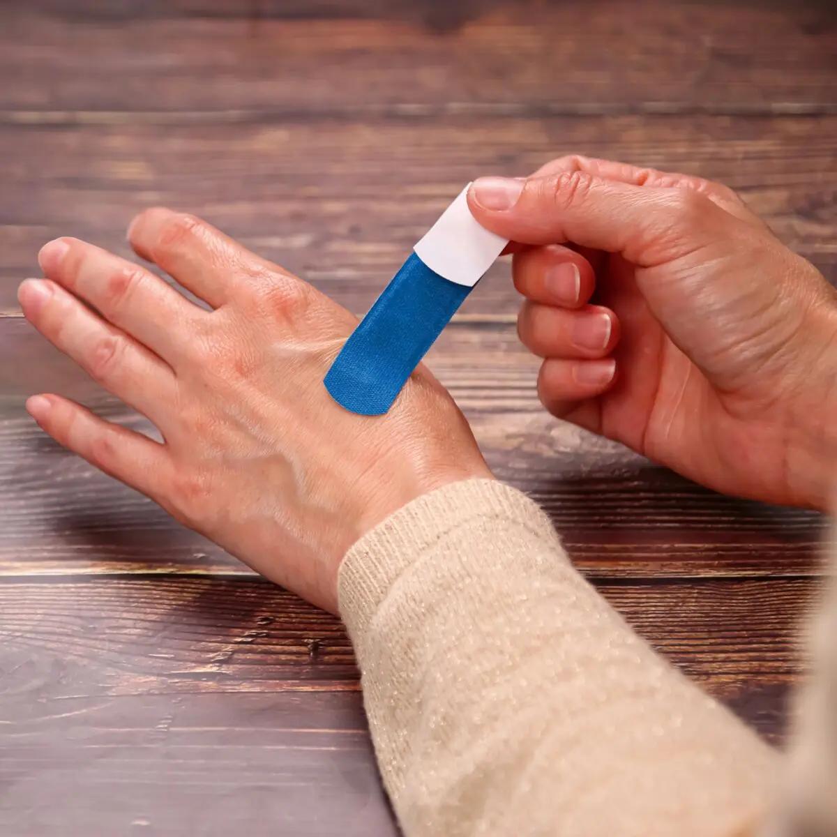 Eine Hand hält einen blauen Werosmart® PowerDetect Pflasterstrip mit extra starker Klebekraft auf dem Ringfinger gedrückt.