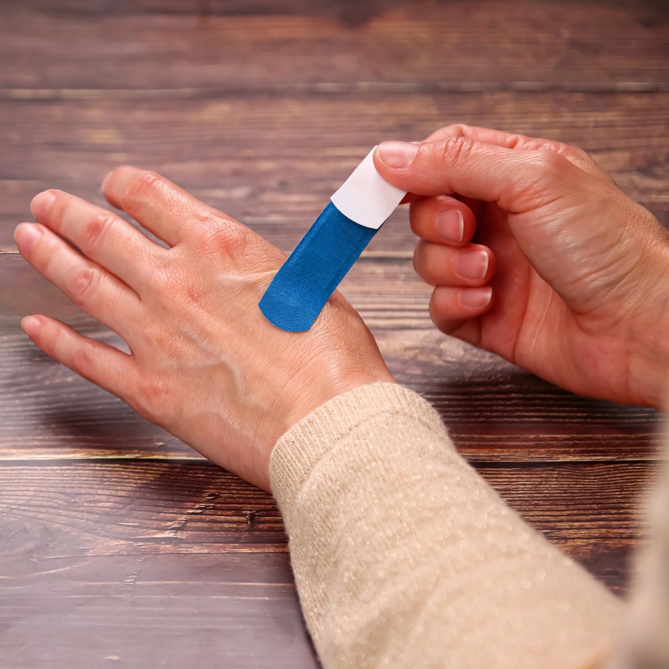 Eine Hand hält einen blauen Werosmart® PowerDetect Pflasterstrip mit extra starker Klebekraft auf dem Ringfinger gedrückt.