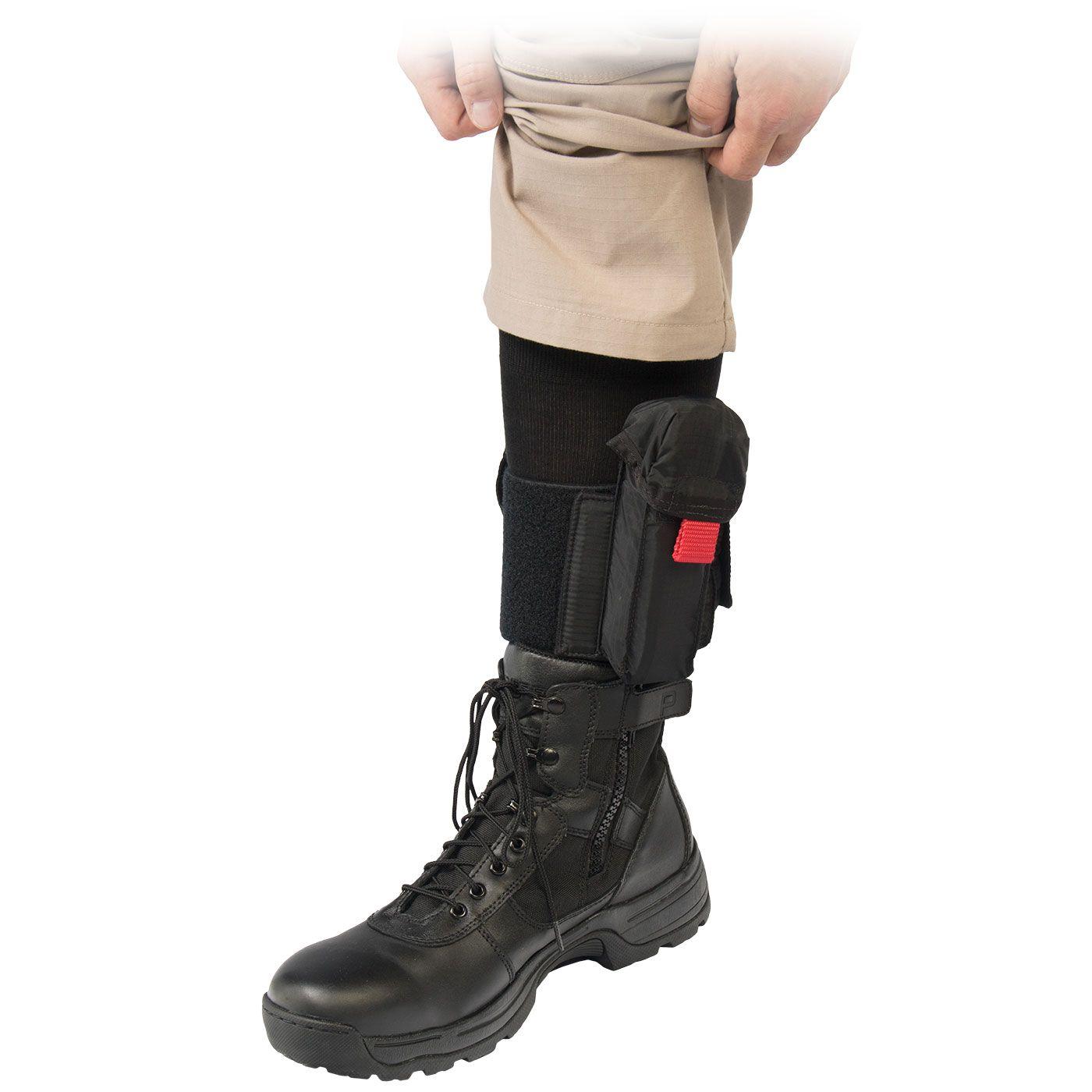 NAR Knöchel Trauma Halter in Schwarz mit Reißverschluss und rotem Label, per Riemen an tanfarbener Cargo-Shorts am Bein befestigt.