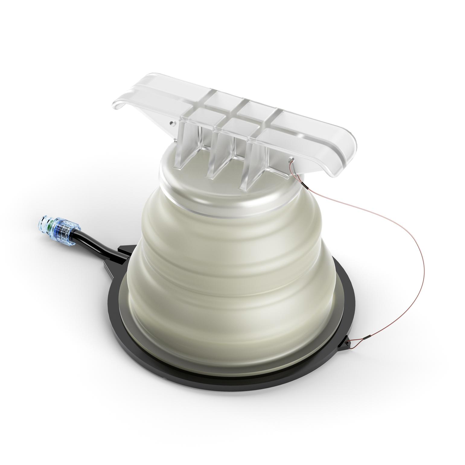 Ein SAM® Junctional Tourniquet mit transparenter Abdeckung, silbernem Ring, tanfarbener Leitung und geriffeltem Korpus auf schwarzem Standfuß.