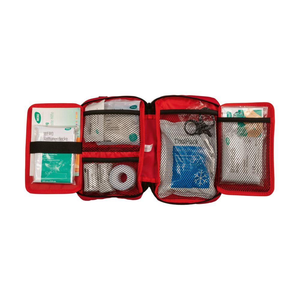 Rotes Erste-Hilfe-Set mit Verbänden, Pflastern, Schere, Desinfektionstüchern, Medikamenten und mehreren Fächern übersichtlich sortiert.