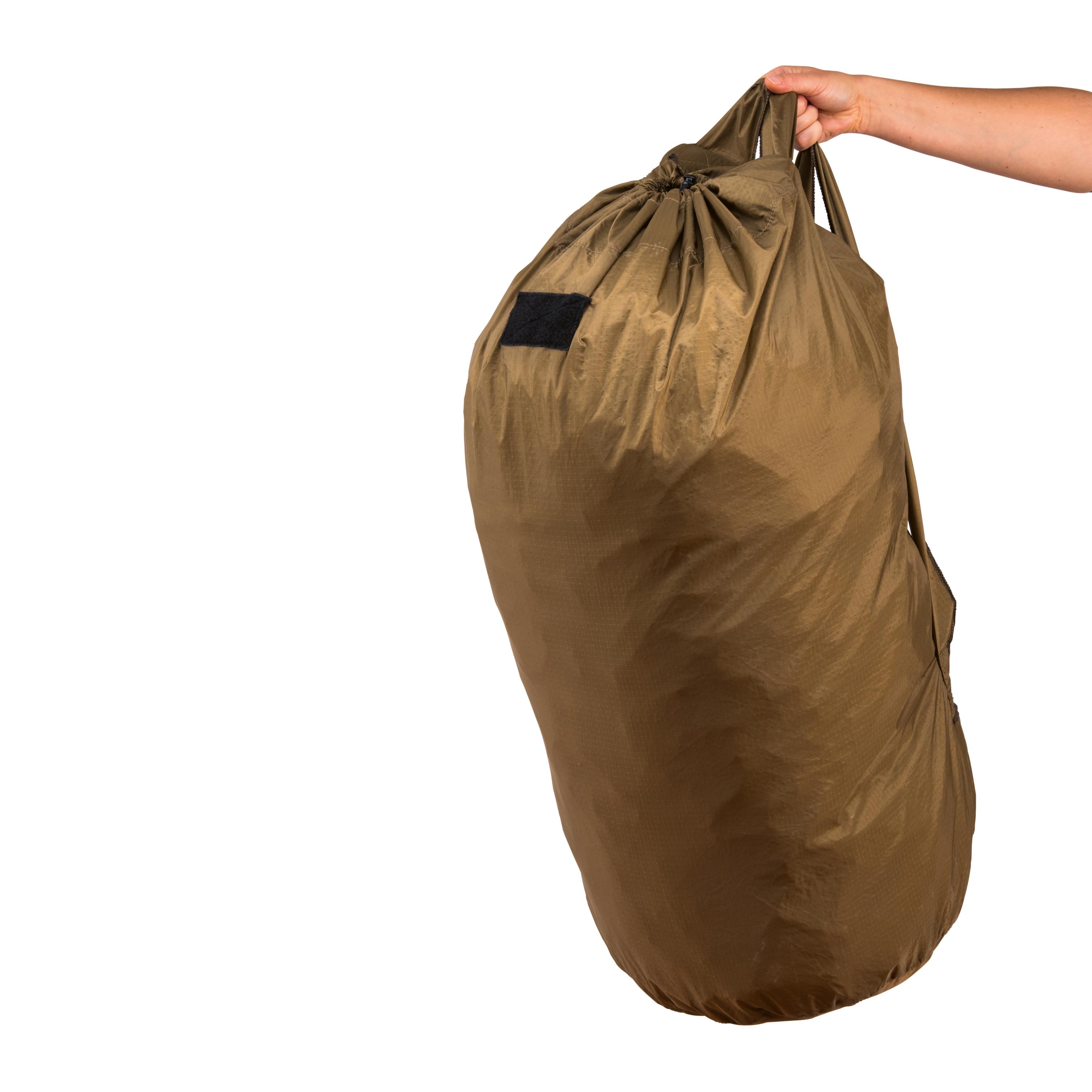 Eine Hand hält die NAR Casualty Equipment Bag aus braunem, robusten Material mit Kordelzug und schwarzem Label, Tragegriff und losen Gurten.