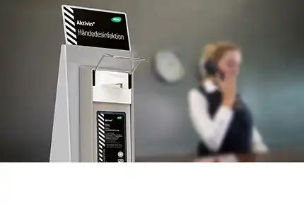 Weißer Activin® Handdesinfektionsspender mit schwarzem Schriftzug und seitlichem Hebel in modernem Innenraum