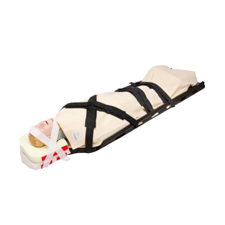 Ein medizinischer Trainingsdummy liegt auf dem CM Trauma Mattress™ Cover mit T-Fix™, mit schwarzen Fixiergurten gesichert und Einmal-Kopffixierung am Kopf.