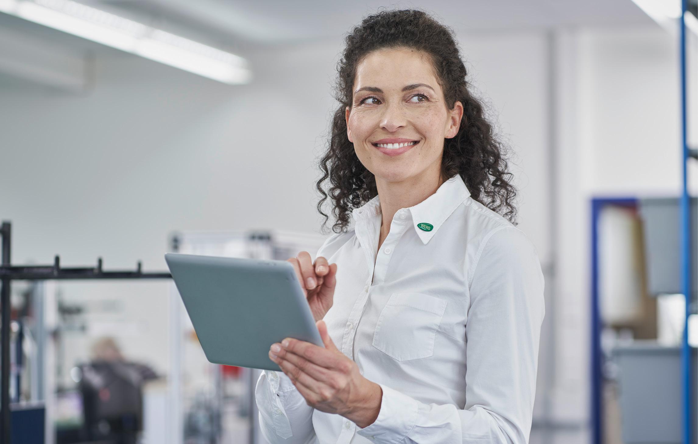 Eine WERO Mitarbeiterin lächelt und bedient das iPad