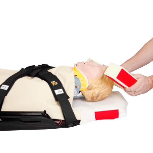 Ein medizinischer Übungsdummy liegt auf dem CM Trauma Mattress™ Cover mit T-Fix™, trägt eine gelbe Halskrause und ist mit einem schwarzen Haltegurt gesichert.