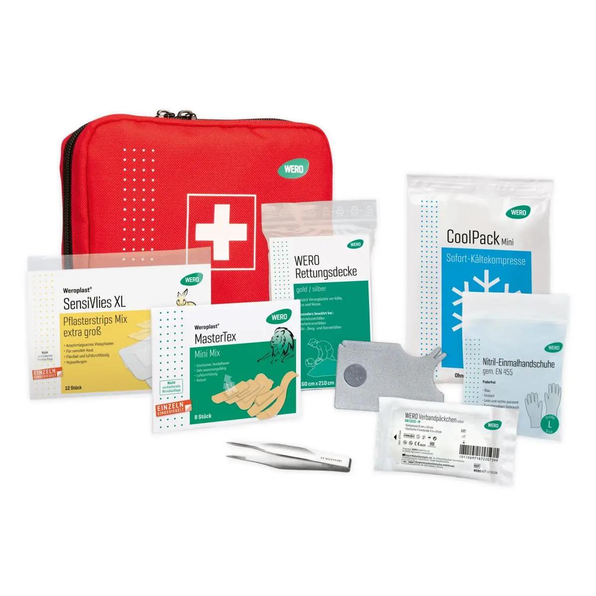 Rotes Erste-Hilfe-Set von Wero, geöffnet, mit sterilem Verbandsmaterial und Zubehör, übersichtlich in sechs Fächern angeordnet.