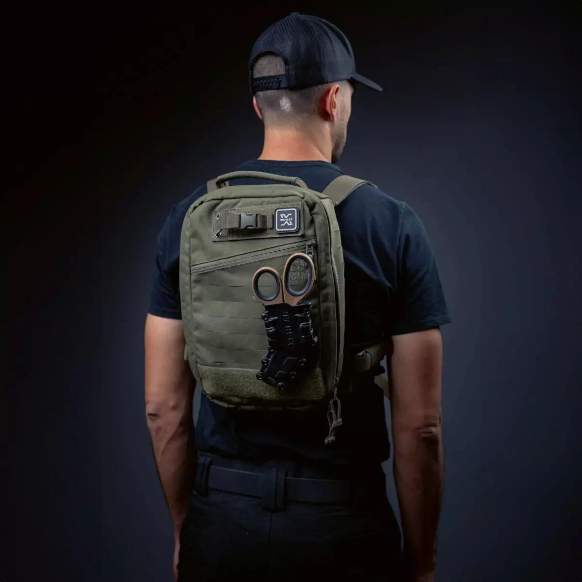 XSHEAR® Gen2 Tactical Holster / Halter wird an einem grünen Hüft-Rucksack getragen, bestückt mit goldfarbenen Scheren und schwarzen Befestigungen.