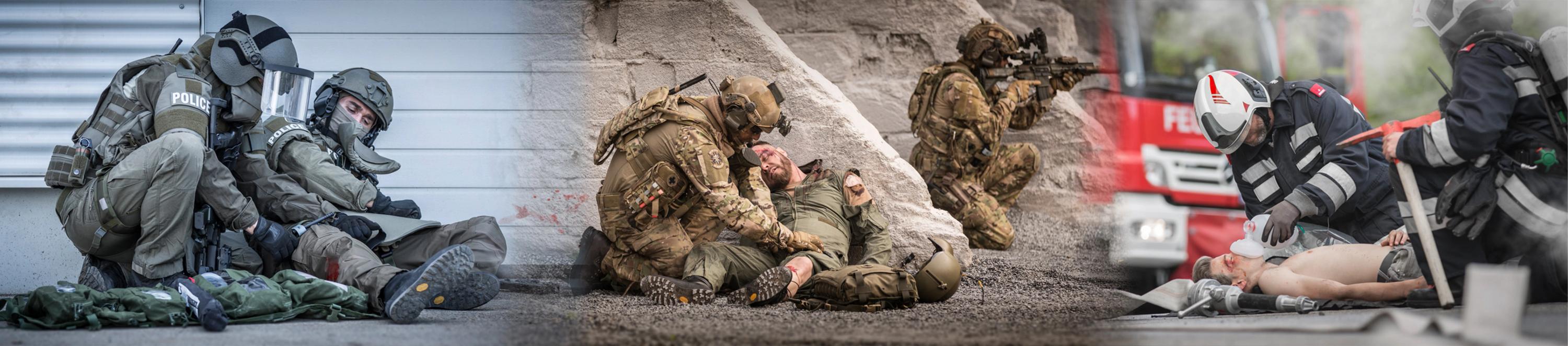 Drei Soldaten in Uniform und Schutzausrüstung leisten Erste Hilfe und bergen Verwundete auf felsigem, unwegsamem Gelände.