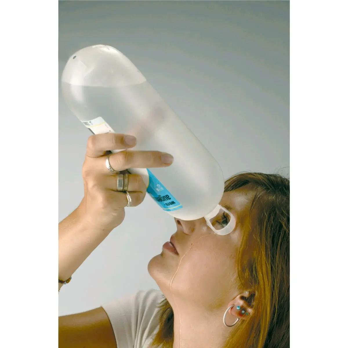 Eine junge Frau tropft mit einer WERO Augenspülflasche Modell P 8 gepufferte Lösung, steril, Flüssigkeit in ihr Auge.