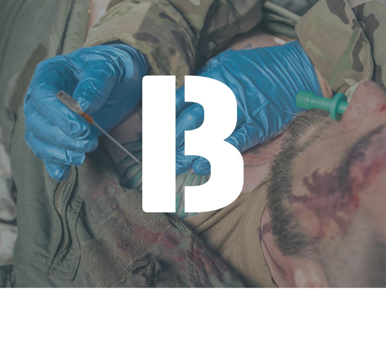Ein Soldat wird mit einer Entlastungspunktionsnadel behandelt. Im Vordergrund ein weißes "B".